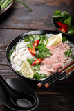Pho Bo vietnamese soup with beef and noodles on a wooden background, selective focus