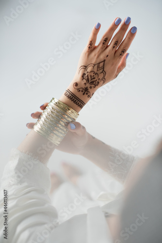 Foto partial view of indian woman with mehndi wearing golden bracelet while getting r