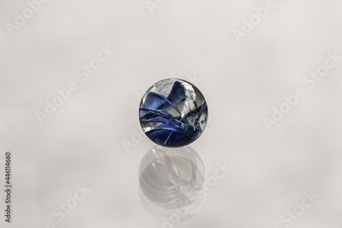 Round dark blue transparent crystal ball  glass stone  marble and its reflection on grey background. Close up