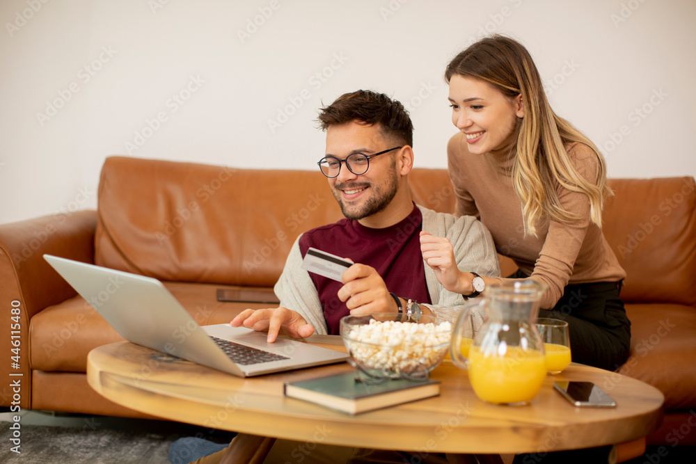 Young couple using laptop together while sitting on sofa at home Young couple using laptop together while sitting on sofa at home