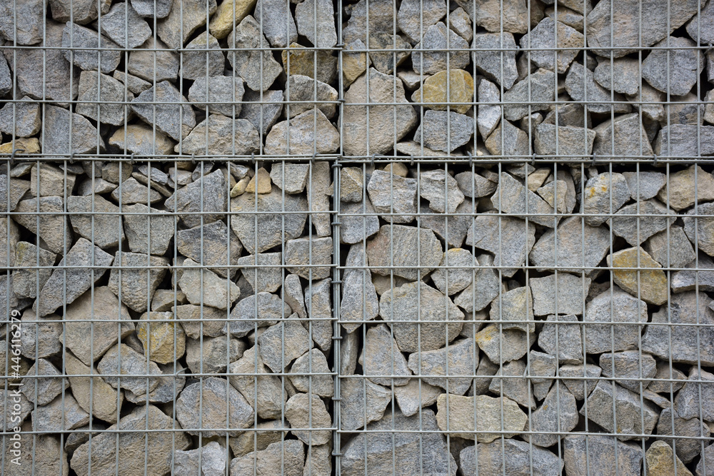 A large fence of many stone boulders supported by a stone trellis for the entire frame