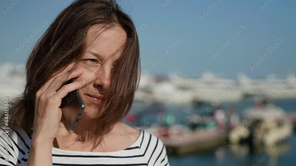 a pretty middle-aged woman is talking on the phone on the street on a sunny morning a pretty middle-aged woman is talking on the phone on the street on a sunny morning