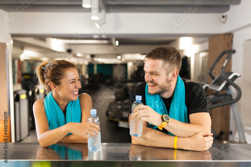 happy couple with towels ismiling and holding water bottles while resting in a fitness club