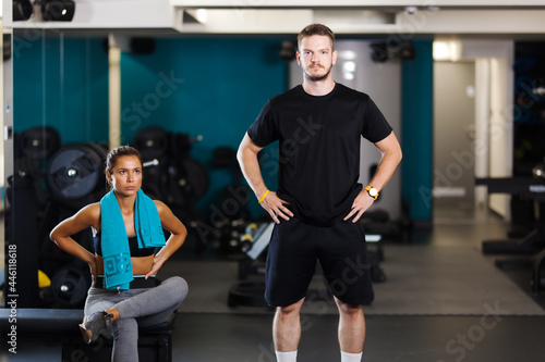 Fitness instructor with a female client. Lovely couple posing in a fitness club.