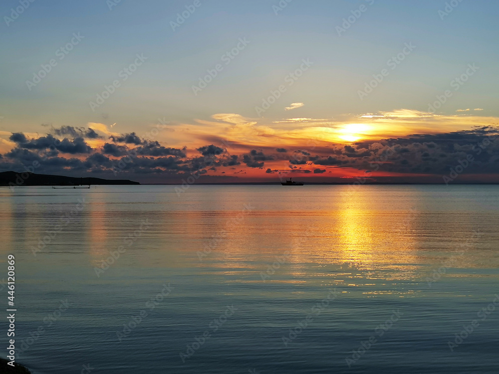Sunset at the sea. Lovely quiet atmosphere. A ship and fishing nets in the distance Sunset at the sea. Lovely quiet atmosphere. A ship and fishing nets in the distance