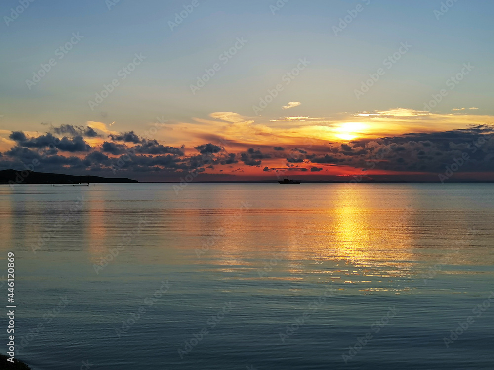 Sunset at the sea. Lovely quiet atmosphere. A ship and fishing nets in the distance