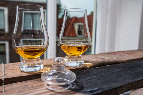 Dram of single malt scotch whisky served in tasting glass with view on old window and houses © barmalini
