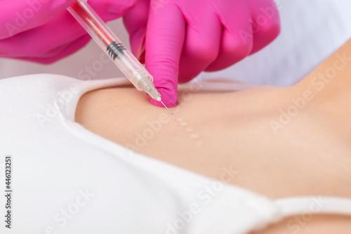 The beautician makes wrinkle injections on the face and neck of a beautiful blonde woman. Women's cosmetology in a beauty salon.