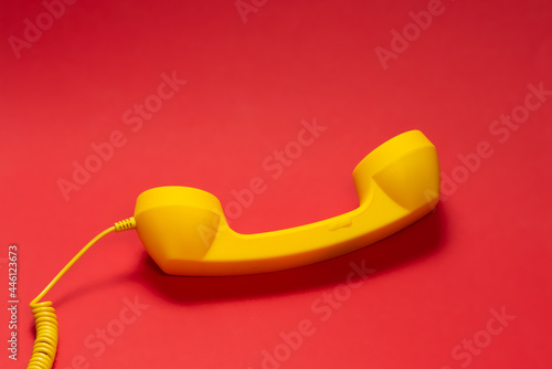 Yellow handset on red background.