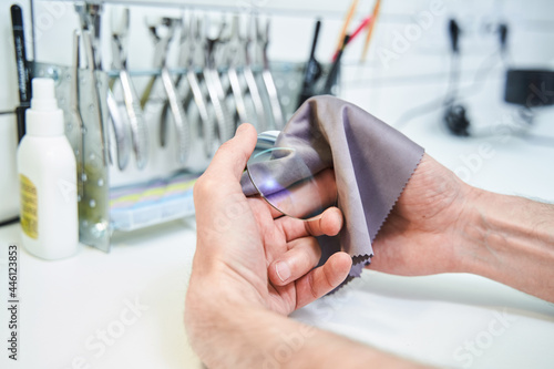 Male optician cleaning lens for eyeglasses in workshop