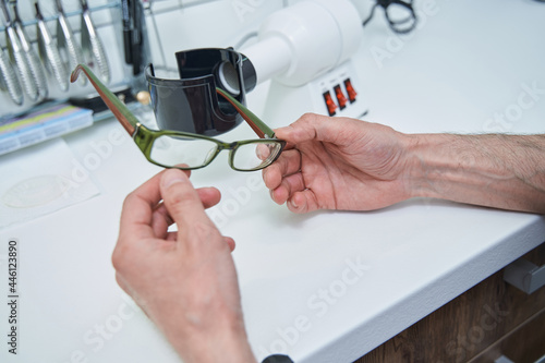 Male optician hands holding eyeglasses with green frame