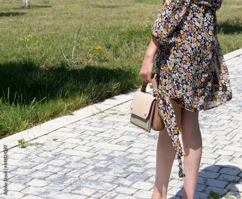 Fashionable beautiful  handbag on the arm of the girl in a fashionable  dress.