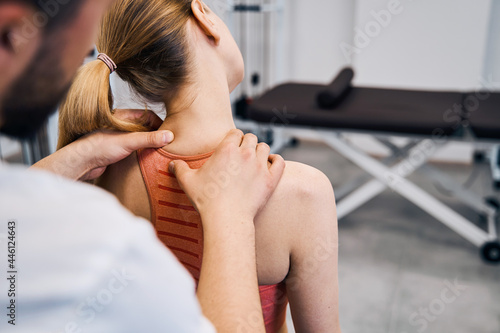 Physiotherapist hand massaging woman painful neck in physic room closeup back view. Recovery therapy photo