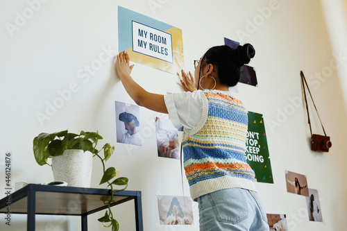 Fotografia Portrait of modern teenage girl hanging My room my rules poster on wall in room,