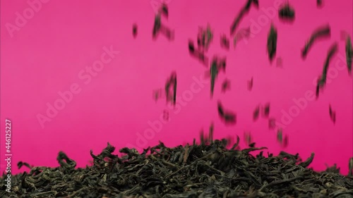 Close-up of falling down dried tea leaves on table on pink background. Shooting of black ceylon tea in studio. Macro footage of pouring out brewed tea into pile. Food and drink cooking video.  photo