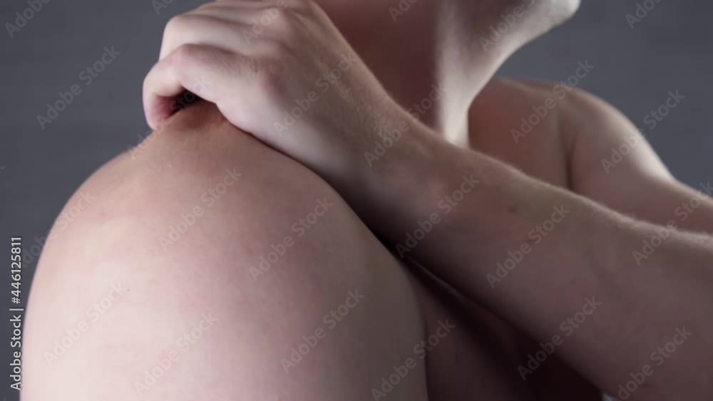 Attractive bearded man suffering from pain in shoulder in the living room. Unhappy man suffering from neck or shoulder pain at home. People, healthcare and problem concept Attractive bearded man suffering from pain in shoulder in the living room. Unhappy man suffering from neck or shoulder pain at home. People, healthcare and problem concept