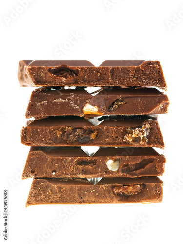 Stack of milk chocolate pieces with nuts and raisins on white background 