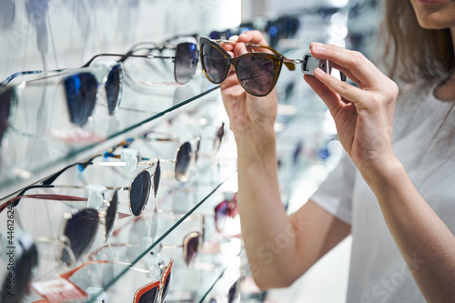 Young woman choosing sunglasses in optical store photo
