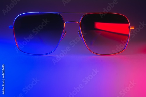 Stylish sunglasses shot using pink and blue abstract colored lighting with copy space. © Serhii