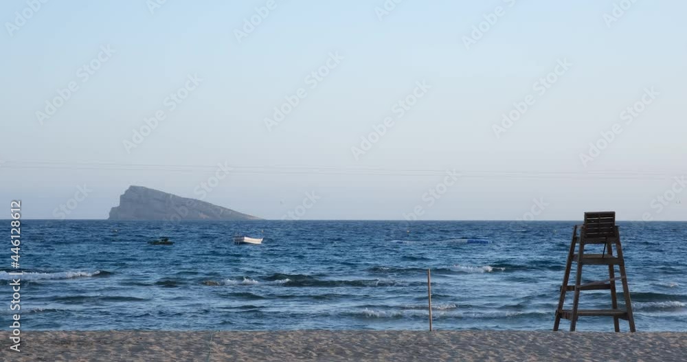 Lifeguard chair on the beach with boat and island in the background