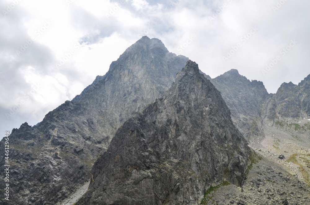 Jagged and sharp ridges rock emerge from the mist above and rain clouds at High Tatras National Park, Slovakia Jagged and sharp ridges rock emerge from the mist above and rain clouds at High Tatras National Park, Slovakia