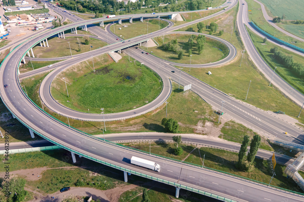 Naklejka premium Motorway with moving cars. Transport interchange. Logistics and delivery of goods. Trucks on the bridge