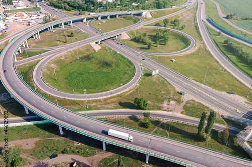 Motorway with moving cars. Transport interchange. Logistics and delivery of goods. Trucks on the bridge