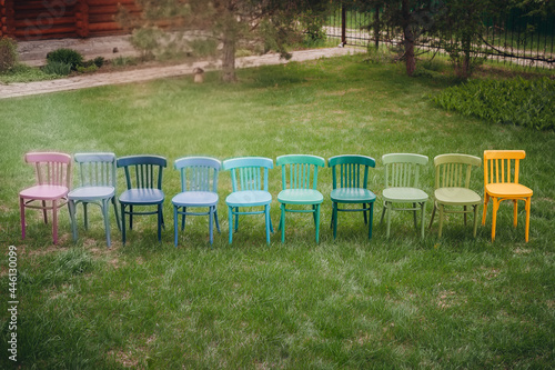 top view of a row of colorful Viennese chairs in a row, a children's birthday party in the garden on the lawn in the backyard at sunset on a warm summer day. © Юля Бурмистрова