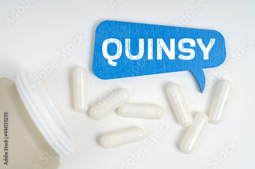 On the table are pills and a blue sign that says - quinsy photo
