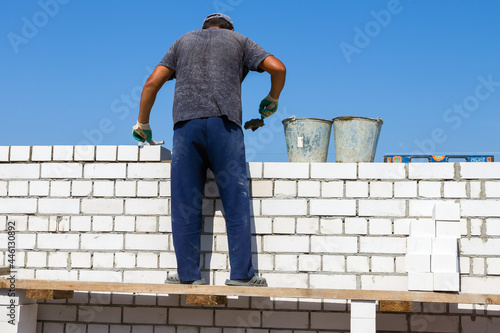 a bricklayer constructs a wall of a building from white sand-lime bricks