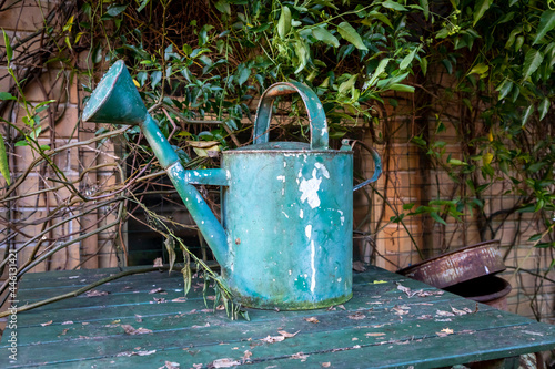 An old watering can on a table in a garden