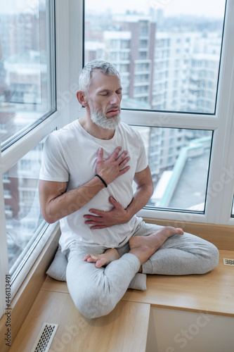 A mature yogi doing pranayama and looking meditative photo