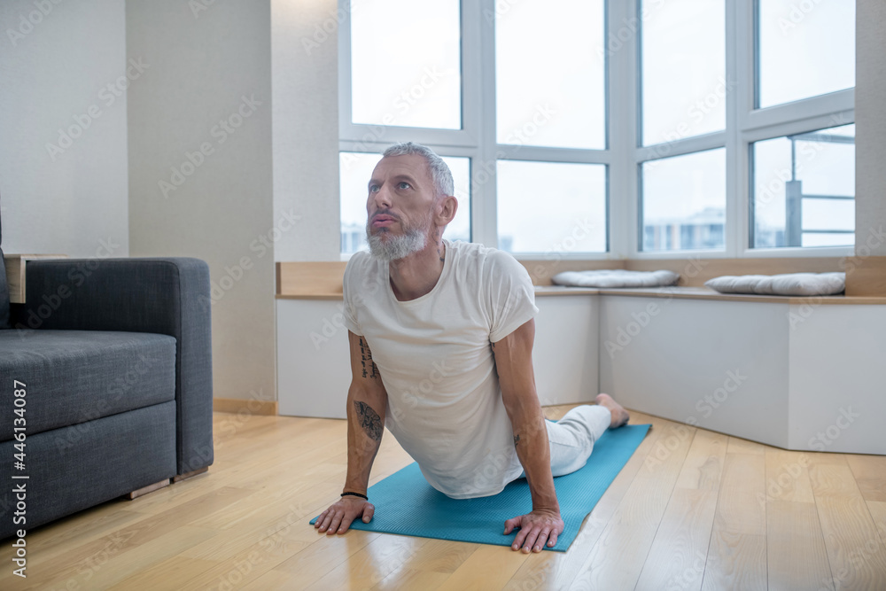 A mature yogi exercising at home and looking flexible