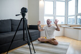 A mature man in white tshirt practising yoga online