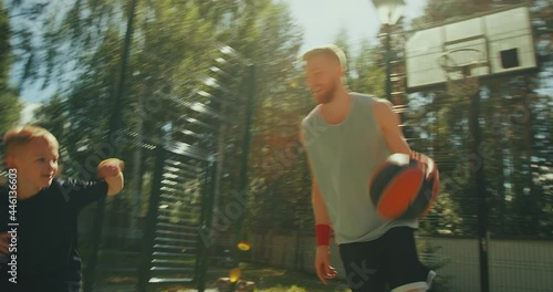 Basketball players sportive family father and son dribbling on basketball court outdoors. Active energetic workout