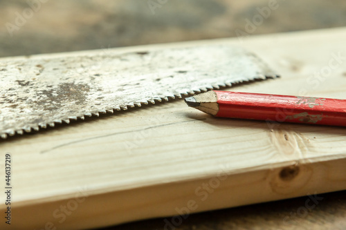 Close-up of a craftsman pencil and a hand saw on a wooden plank © Annabell Gsödl