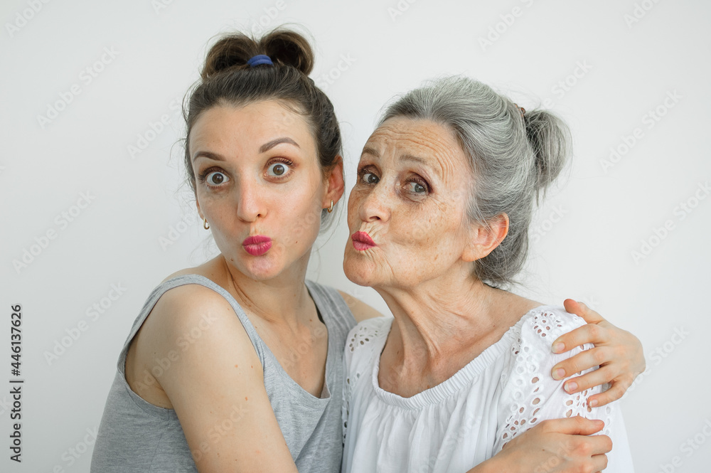 Happy senior mother is hugging her adult daughter, the women are laughing together, sincere family of different age generations having fun on white background, mothers day. Happy senior mother is hugging her adult daughter, the women are laughing together, sincere family of different age generations having fun on white background, mothers day.