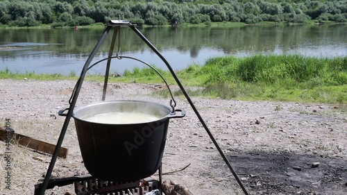 cooked on the background of nature on a fire in a cauldron of boiling water photo