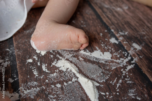 small children's feet in flour on a wooden background