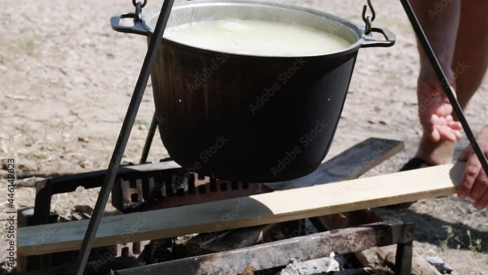 A man chopping wood on the background of a pot on a fire A man chopping wood on the background of a pot on a fire