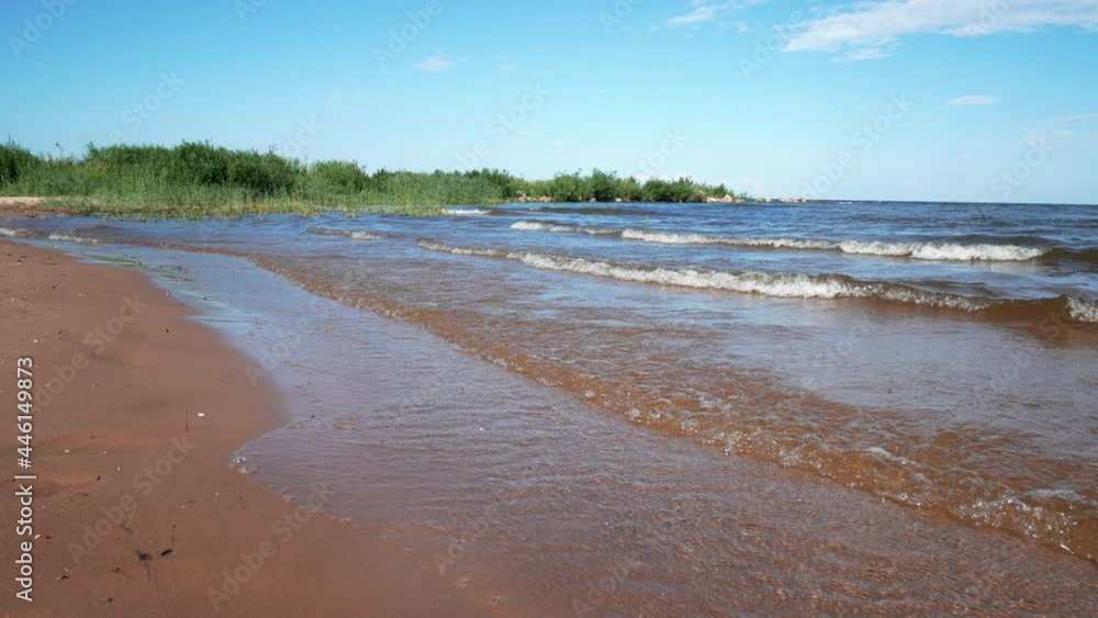 Nature and travel concept. Waves crashing into a sandy beach on a sunny summer day. Empty beach with lake view. Nature and travel concept. Waves crashing into a sandy beach on a sunny summer day. Empty beach with lake view.