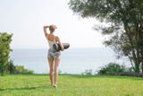 Outdoor portrait of beautiful Caucasian woman holding exercise mat before yoga class. Yoga exercise concept.