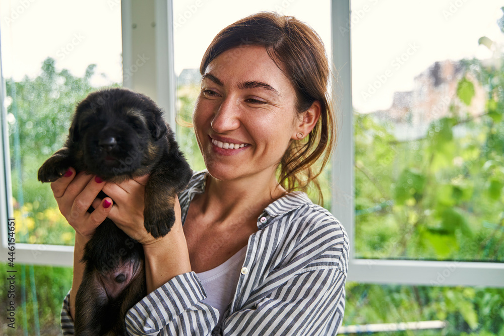 Happy woman spending time with cute black puppy - obrazy, fototapety, plakaty 
