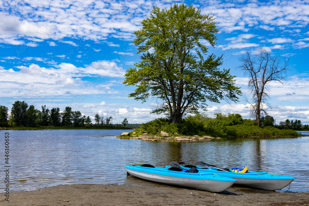 Two blue kayaks resting on the beach by an island Two blue kayaks resting on the beach by an island