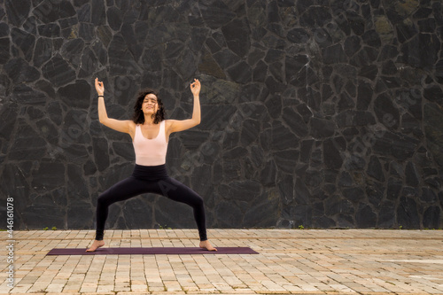 Young woman with curly hair in standing yoga pose and closed eyes