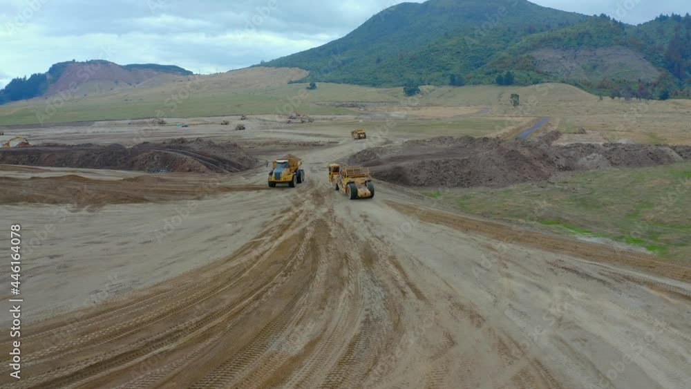 Earthwork vehicles pass each other on dirt road on large construction site, aerial Earthwork vehicles pass each other on dirt road on large construction site, aerial