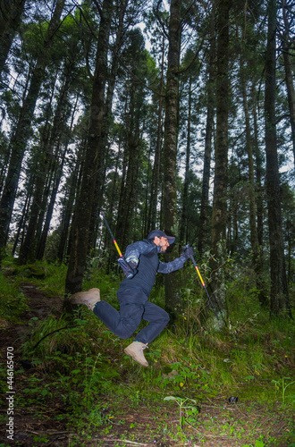 man jumping in the forest with walking sticks