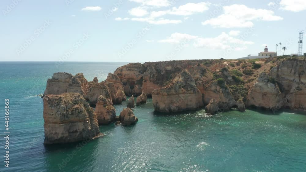Drone descending towards eroded cliffs surrounded in a blue sea Drone descending towards eroded cliffs surrounded in a blue sea
