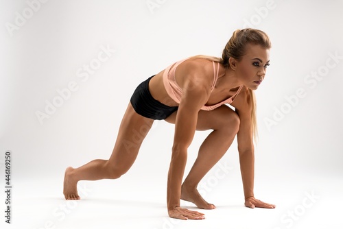 Athletic woman standing in low start position in studio