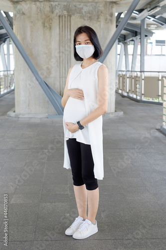 A pregnant woman wearing casual clothes is vaccinated and shows plaster on her upper arm. photo